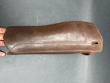a person holding a brown leather case on a gray surface