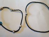paire de bracelets en cuir noir ornés de perles argentées et d'une perle bleue