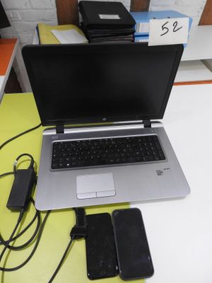 a laptop computer sitting on a desk with a charger and a cell phone