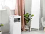 un climatiseur blanc posé dans une pièce, à côté d'un miroir