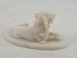 a small statue of a lion laying on a white surface