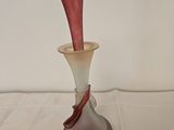 a glass vase with a red handle sitting on a table