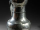 un vase en argent posé sur une table, sur fond noir