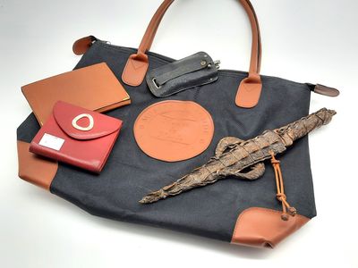 un sac noir muni d'une poignée marron et sur lequel sont posés quelques autres objets