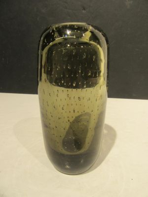 un vase noir et jaune posé sur une table blanche