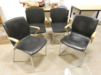 four black leather office chairs with chrome legs in a room