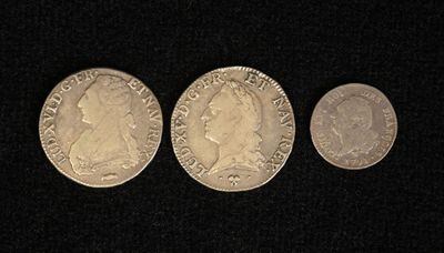 three silver coins are shown in a row on a black surface