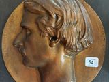 une plaque en bronze représentant un homme avec une coupe de cheveux