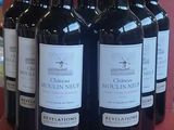 six bottles of red wine are lined up on a red table