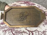 quelqu'un tient une plaque en laiton sur laquelle est représenté un oiseau