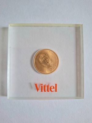 an image of a gold coin in a clear box with the word vittel on it