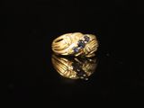 a gold ring with blue sapphires on a black surface
