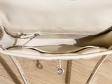 beige leather purse sitting on top of a wooden floor next to a wall
