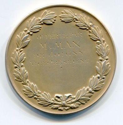 une médaille d'or ornée d'une couronne, posée sur un fond blanc