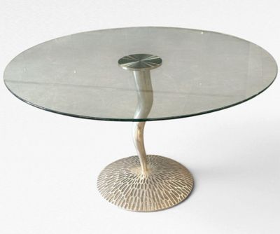 une table en verre avec un piètement en métal, posée sur un sol blanc