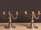 une paire de chandeliers anciens en métal argenté posés sur une table en bois