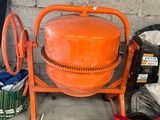 une bétonnière orange à côté d'un seau de ciment