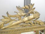 a gold mirror with a bird on it in a room