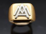 un gros plan d'une bague en or et en argent ornée d'un symbole représentant une montagne