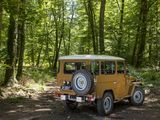 a yellow jeep parked on a dirt road in the woods