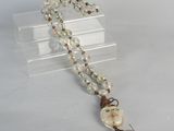 collier composé de perles de verre, orné d'un pompon, sur un fond blanc