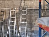 Plusieurs échelles sont alignées contre un mur dans un entrepôt.