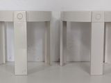 two white tables sitting next to each other on a white floor