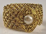 an image of a close up of a gold bracelet with a pearl in it
