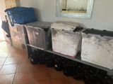 Plusieurs bacs remplis de vêtements sont empilés sur une étagère métallique dans une pièce.