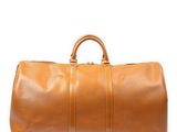 un sac de voyage en cuir marron posé sur une surface blanche