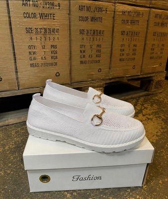 La boîte à chaussures est remplie de chaussures blanches et d'une paire de chaussures blanches.
