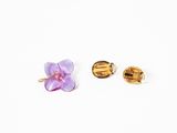 two pairs of gold and purple flower earrings on a white surface