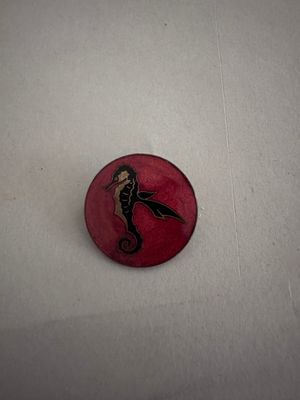 une image représentant un bouton rouge orné d'un hippocampe noir