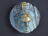 a blue plate with a face on it on a black surface