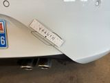 the rear end of a white car with a sticker on it