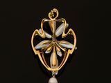 a close up of a gold and pearl broochle on a black surface