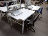 une table blanche sur laquelle est posé un ordinateur portable, dans un entrepôt