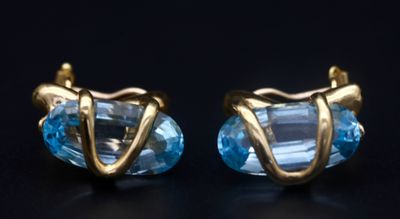 paire de boucles d'oreilles dorées ornées de cristaux de topaze bleue sur fond noir