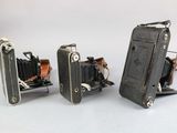 three old cameras sitting next to each other on a white surface