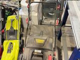 Plusieurs tondeuses à gazon sont alignées dans un garage où se trouvent également des outils.