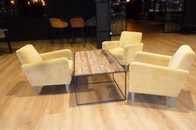 several chairs and a table in a room with a bar in the background