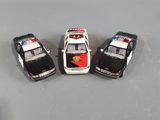 three toy police cars are lined up in a row on a gray surface