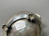 an antique silver plate with a turtle on it on a gray surface