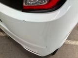the rear end of a white car with a red tail light