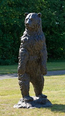une statue représentant un ours debout sur un rocher, au milieu de l'herbe