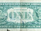 a close up of a one dollar bill on a wooden surface