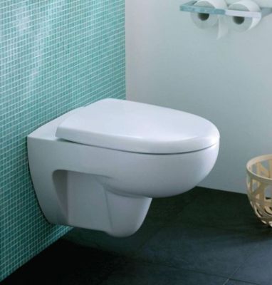 des toilettes blanches situées dans une salle de bains, à côté d'un panier rempli de papier toilette