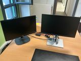 two monitors sitting on a desk next to each other