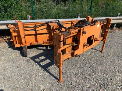 une grosse machine orange qui est posée sur le gravier