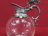 un pichet ancien en verre, orné d'une anse en forme de dragon sur fond rouge